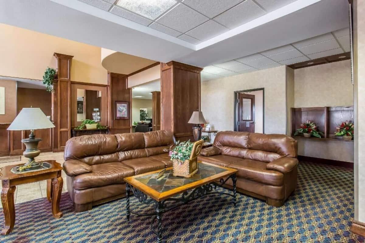 A lobby with leather sofas, a coffee table, lamps, and a patterned carpet.