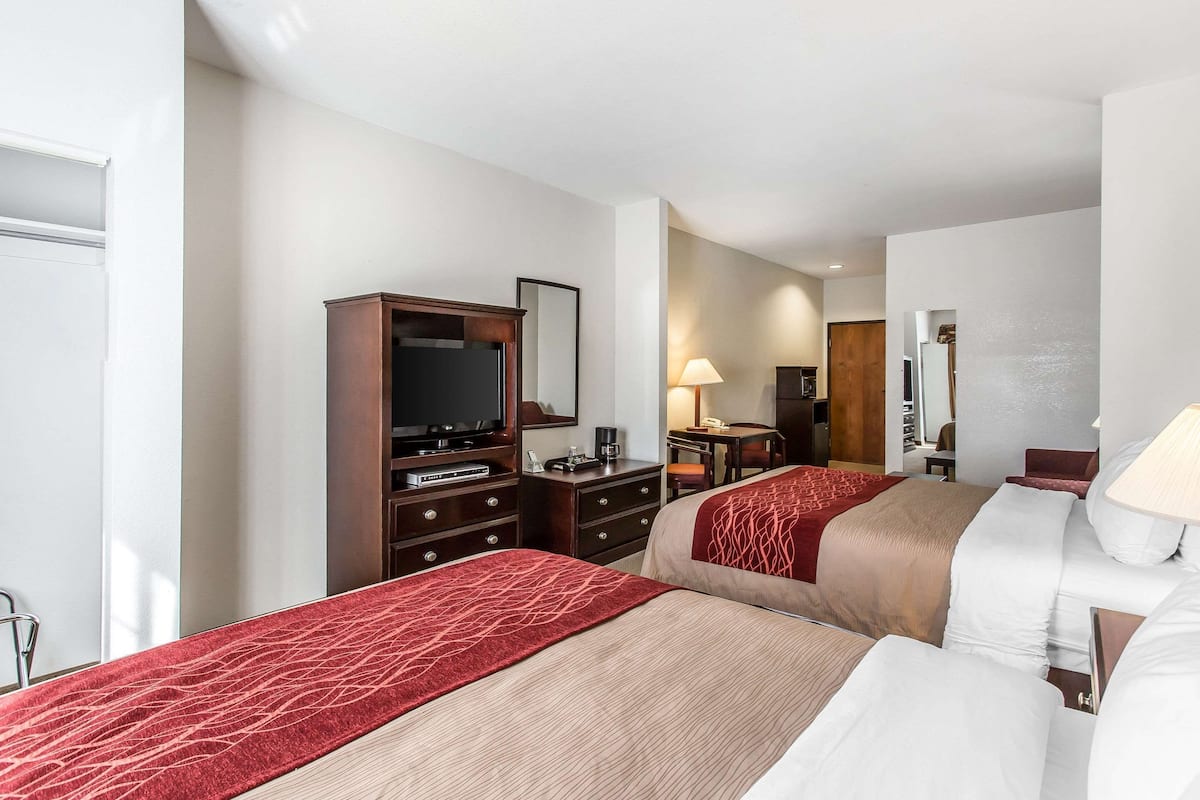 A hotel room with two beds, a desk, a television, and a wardrobe.