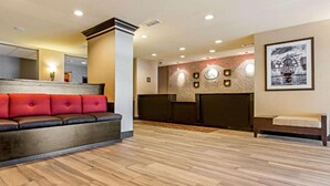 A lobby with a leather sofa, a reception desk, and a wall-mounted clock. - Comfort Suites Fairview Heights - St. Louis (Fairview Heights)
