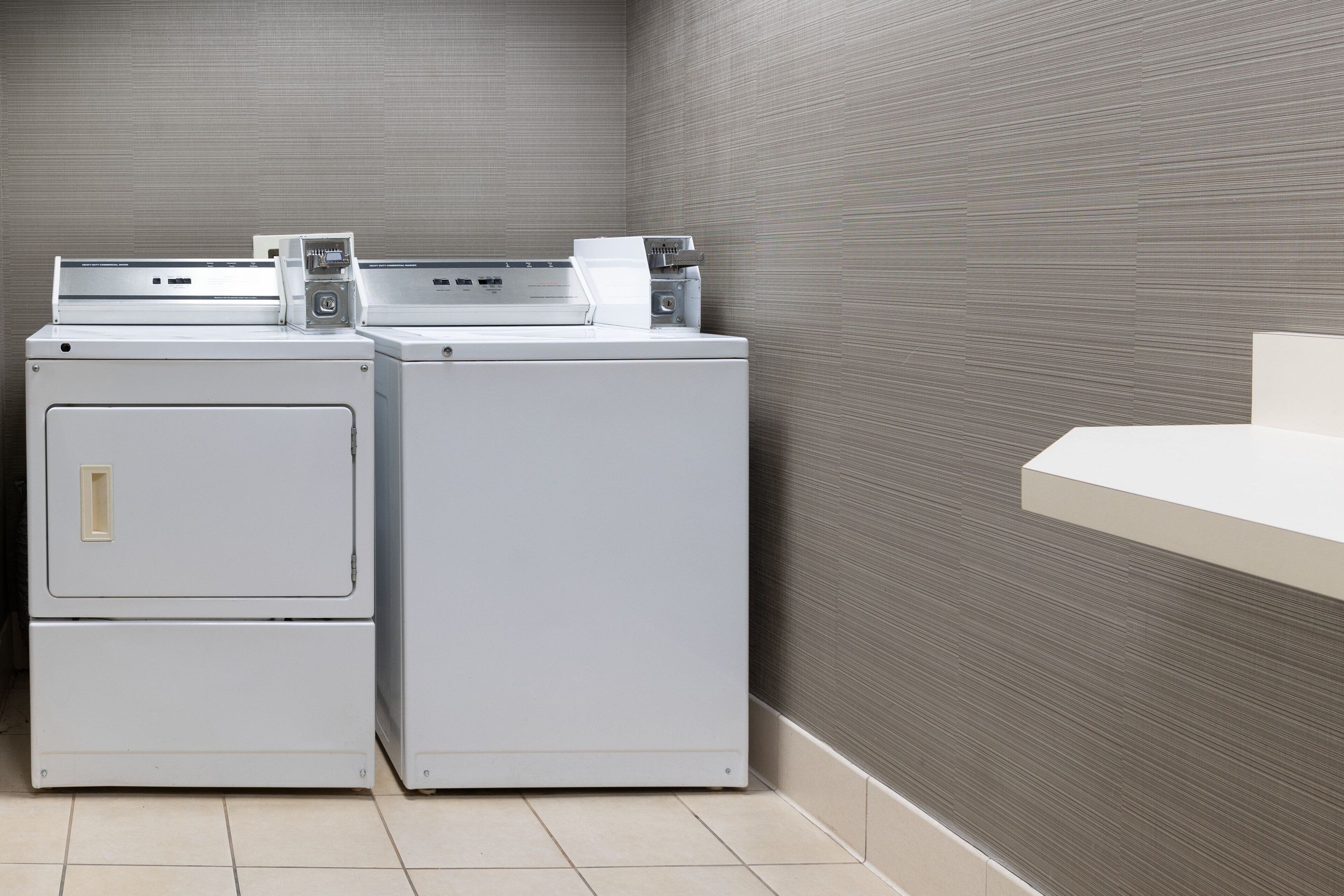 A laundry area with two stacked washing machines and a sink.