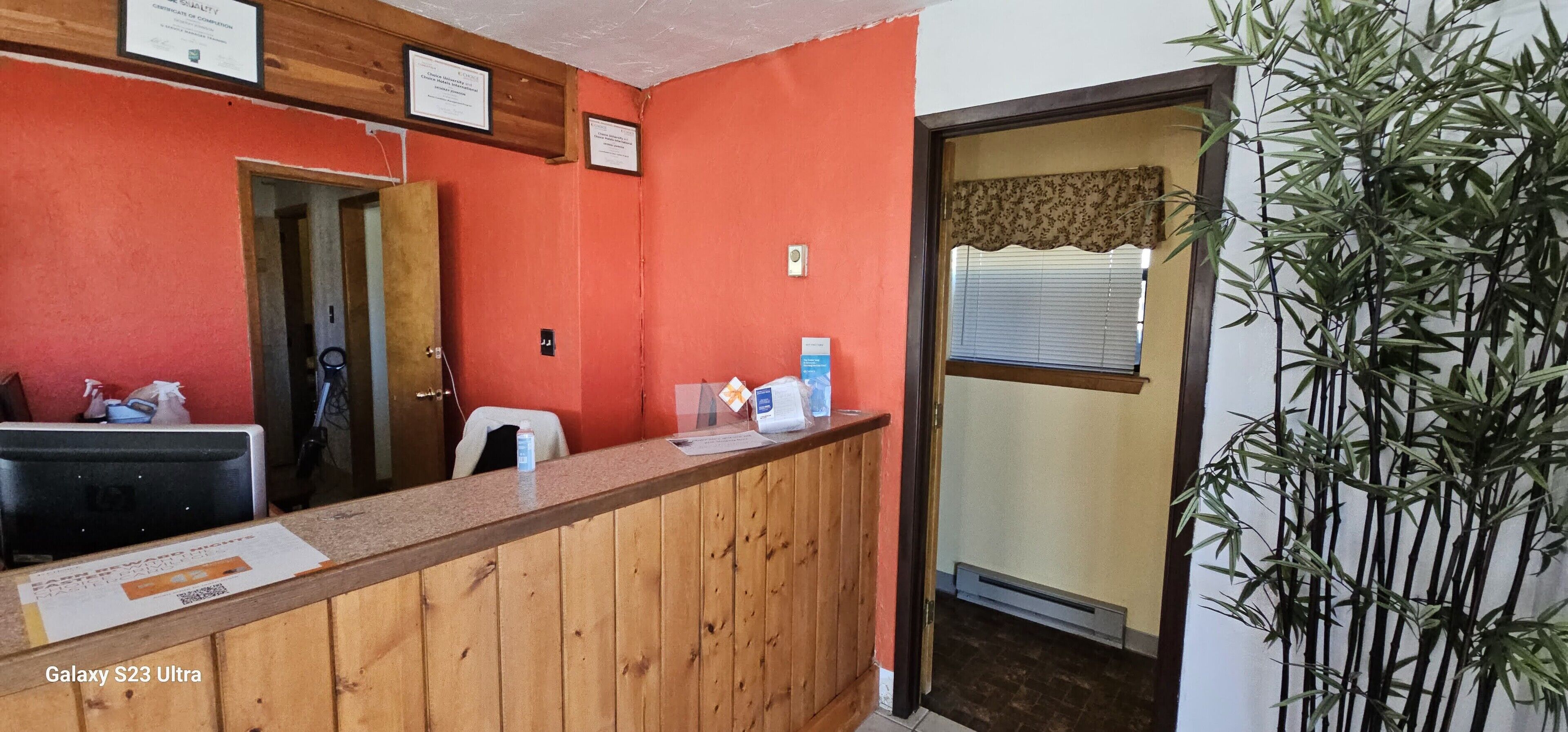 Un espace d’accueil avec un comptoir en bois, une chaise et une porte donnant sur une autre pièce.
