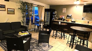A living room with a sofa, coffee table, and chairs, a kitchen area with a bar, and a large window with a view. - Econo Lodge Eagle Nest (Eagle Nest)
