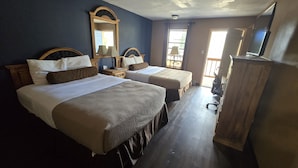 Une chambre d’hôtel avec deux lits, une commode en bois, un miroir et une fenêtre avec des rideaux.