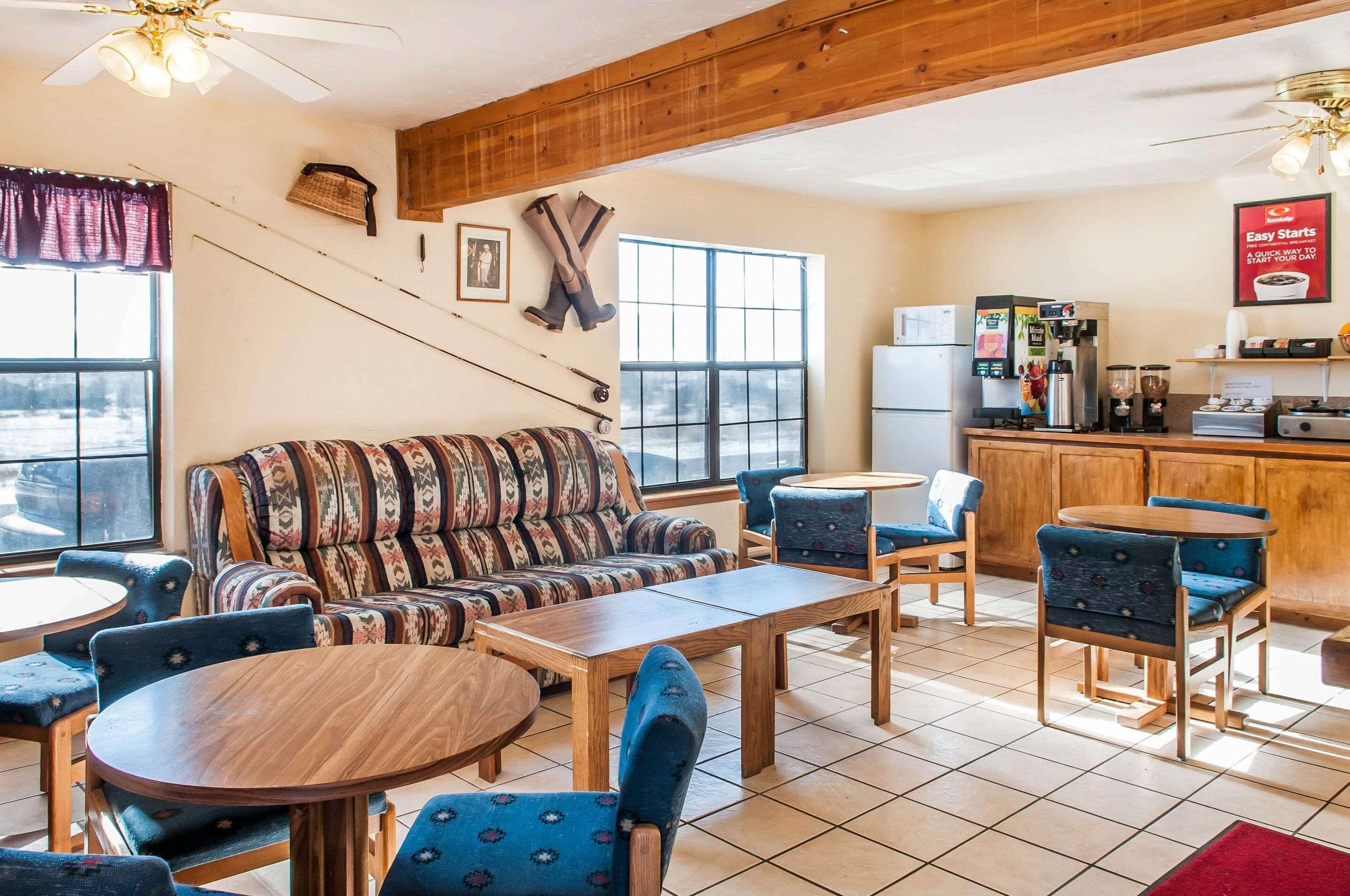 A cozy interior with a sofa, chairs, a dining table, and a kitchen area with a refrigerator and coffee machine.