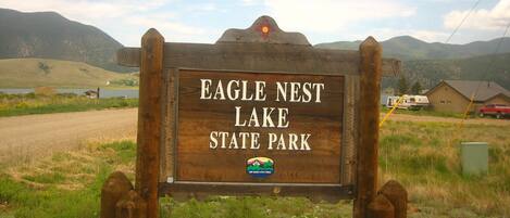 A wooden sign for Eagle Nest Lake State Park with a mountain backdrop.
