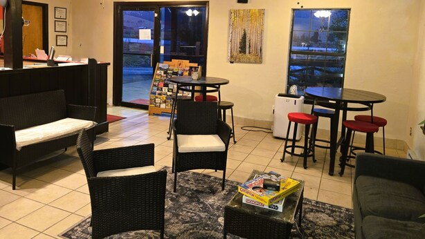 A cozy indoor seating area with wicker furniture, a coffee table, and a small bookshelf. - Econo Lodge Eagle Nest (Eagle Nest)