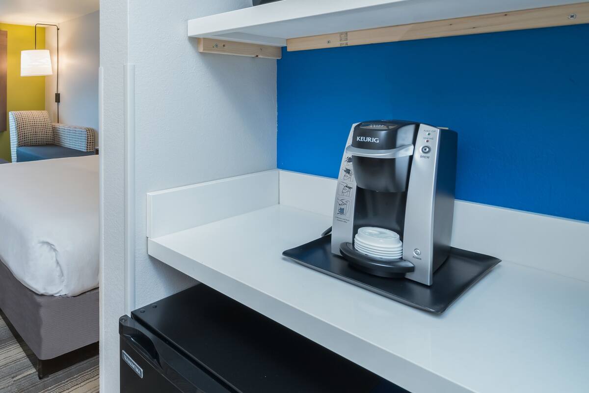 Una kitchenette con un microondas en el estante superior y una cafetera en el inferior.
