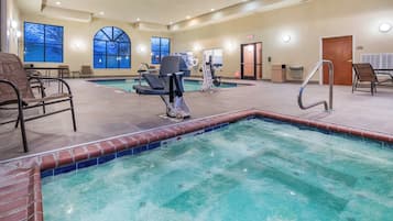 An indoor swimming pool with a lifeguard chair, lounge chairs, and a water slide.