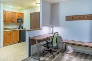 Una kitchenette compacta con armarios de madera, un microondas y una cafetera.