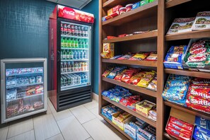 Ein Bereich mit Snacks und Getränken, mit Regalen voller verschiedener Snacks und einem Kühlschrank mit Getränken.