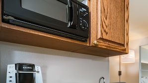 Una kitchenette compacta con microondas, cafetera y lavabo.