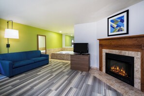 Ein Hotelzimmer mit einem blauen Sofa, einem Flachbildfernseher, einem Kamin und einem großen Spiegel.