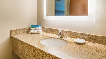 Un baño con encimera de granito, un lavabo blanco y un espejo encima.