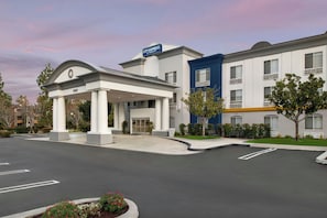 A hotel with a covered entrance, a blue building, and a parking lot. - City Express By Marriott Rancho Cucamonga (Rancho Cucamonga)