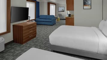 A hotel room with a bed, a television, a blue sofa, a desk, and a chair.