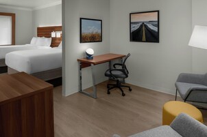 Una habitación de hotel con cama, escritorio, silla de oficina y dos sillones.