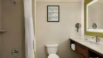 A bathroom with a toilet, a sink, a mirror, and a shower curtain.