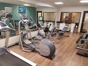 A gym with various exercise equipment, including treadmills, elliptical machines, and weight benches.