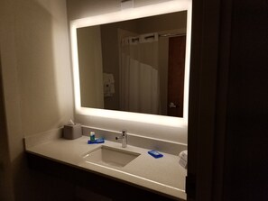 Een badkamer met een grote spiegel, een wastafel en een handdoekhouder.