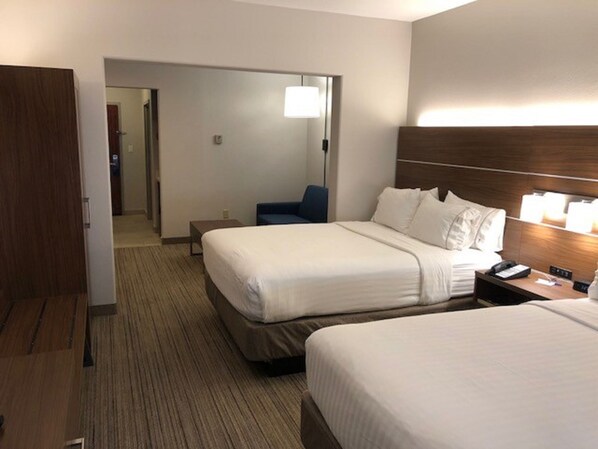 Een hotelkamer met twee bedden, een bureau, een stoel en een lamp.