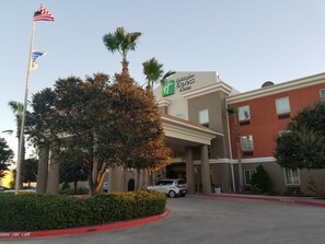 A Holiday Inn Express & Suites building with a parking lot, a flagpole with the American flag, and a palm tree. - Holiday Inn Express & Suites Rio Grand by IHG (Rio Grande City)