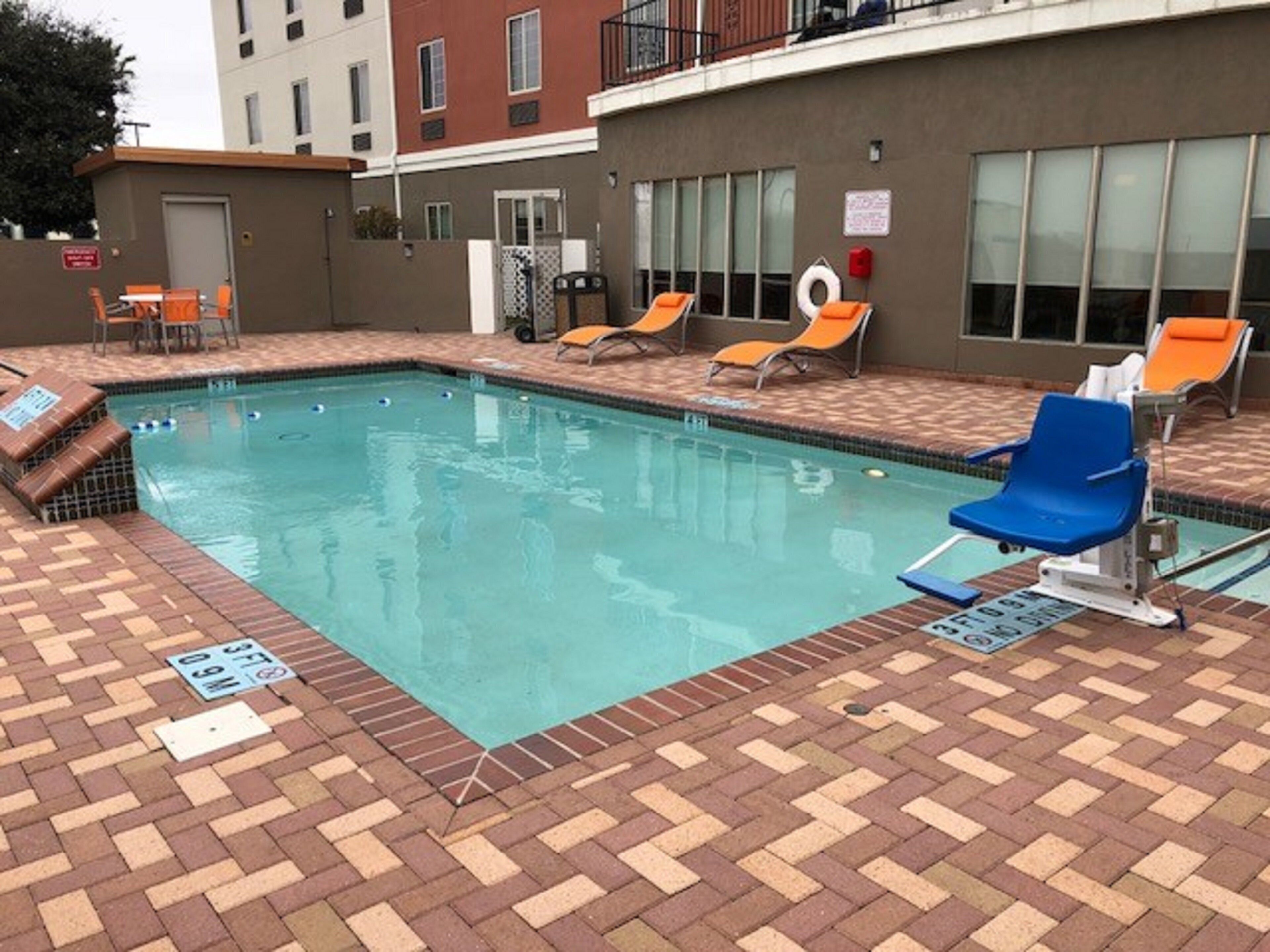 Una piscina con sillas de descanso y solárium de ladrillo.