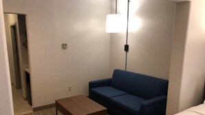 A hotel room with a blue sofa, a wooden coffee table, and a bed. - Holiday Inn Express & Suites Rio Grand by IHG (Rio Grande City)