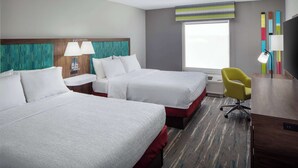 Habitación de hotel con dos camas, un escritorio, una silla y un televisor.