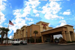 A Hampton Inn hotel with a clear blue sky and clouds.