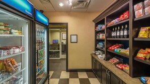 A grocery store with a checkered floor, refrigerated section, and shelves stocked with snacks and beverages.