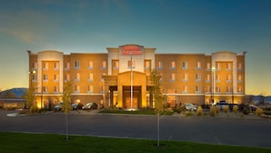 A Hampton Inn & Suites hotel with a central entrance, multiple floors, and a parking lot.