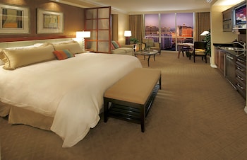 A compact kitchen with a central island, wooden cabinets, a stainless steel refrigerator, and a microwave. at The Signature at MGM Grand (All Suites)