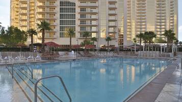 Una piscina al aire libre, camas de piscina con cargo, sombrillas
