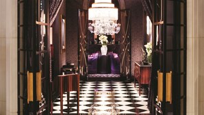 A grand entrance with a chandelier, checkered floor, and a sign reading "JOEL ROBUCHON".