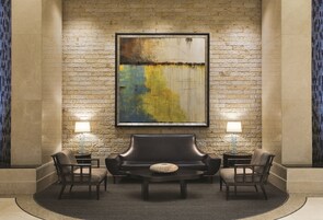 Un hall con pared de piedra, un cuadro abstracto grande, dos sofás y dos lámparas.