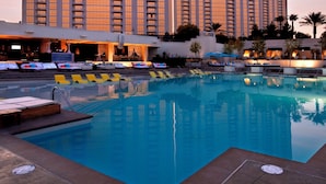 A hotel with a pool area, multiple high-rise buildings, and a clear sky.