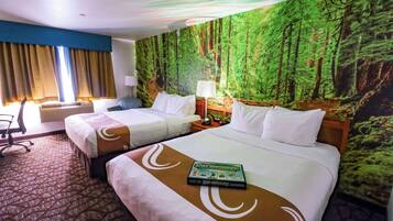 Habitación de hotel con dos camas, un mural grande con motivos forestales en la pared, un escritorio con lámpara y un equipo de aire acondicionado.