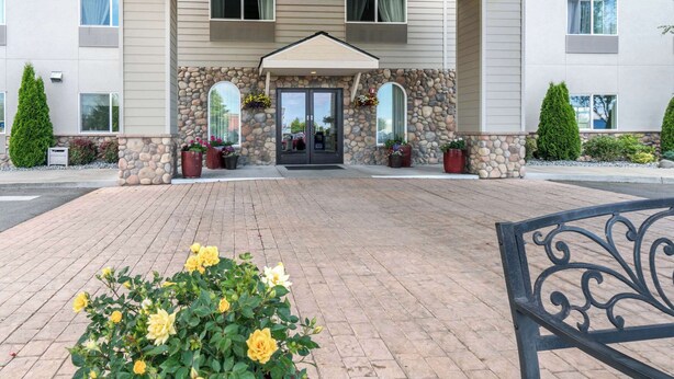 A hotel entrance with a stone facade, a covered entryway, and potted plants. - Quality Inn & Suites Sequim at Olympic National Park (Sequim)