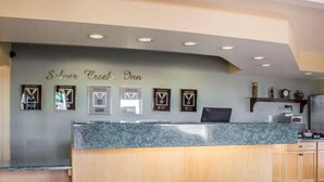 A hotel reception desk with a marble top and wooden paneling. There are framed awards on the wall above the desk. - Rodeway Inn Silver Creek Inn (Snowflake)