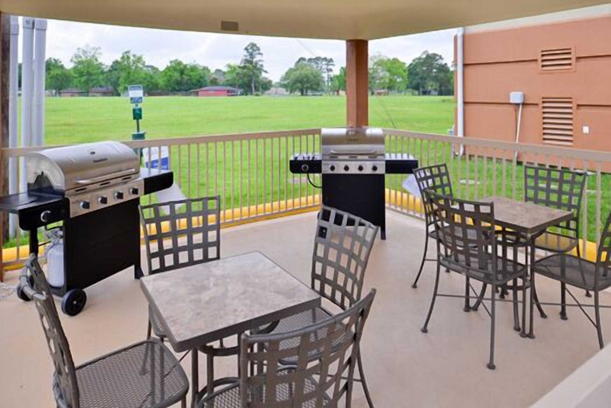 An outdoor patio with a grill, a table, and chairs.