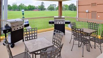 An outdoor patio with a grill, a table, and chairs.