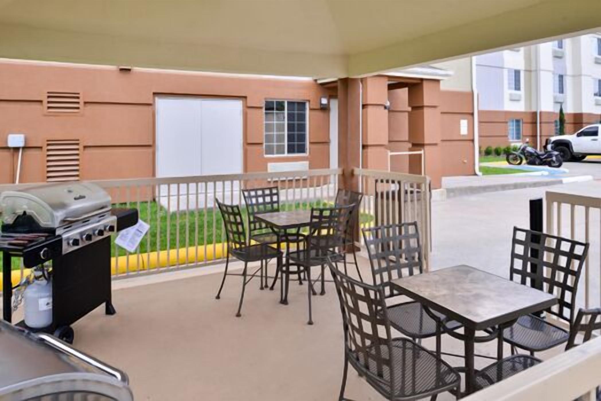 Une terrasse extérieure équipée d’un barbecue, de tables et de chaises.