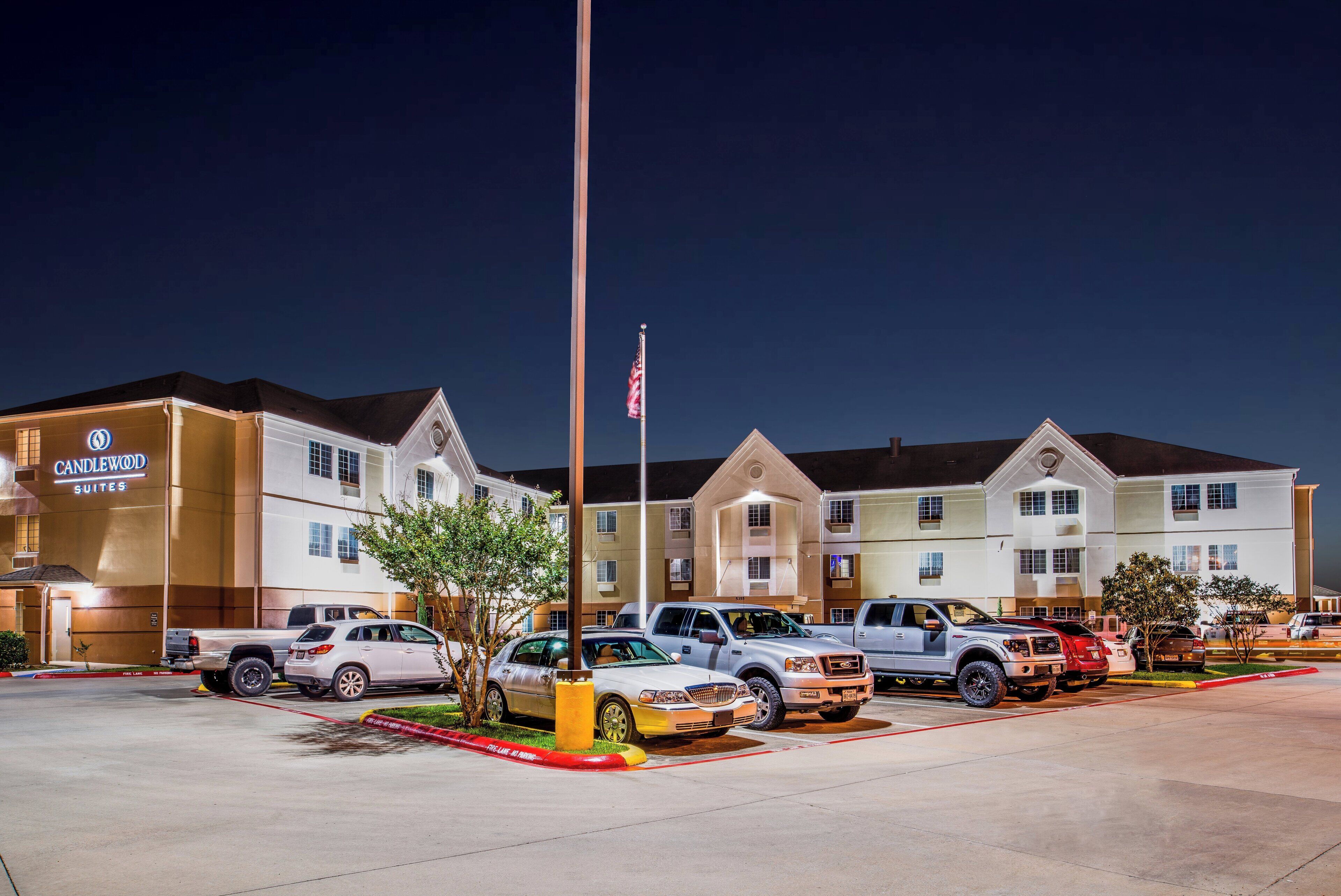 Een hotel met meerdere suites en een parkeerplaats met diverse voertuigen.