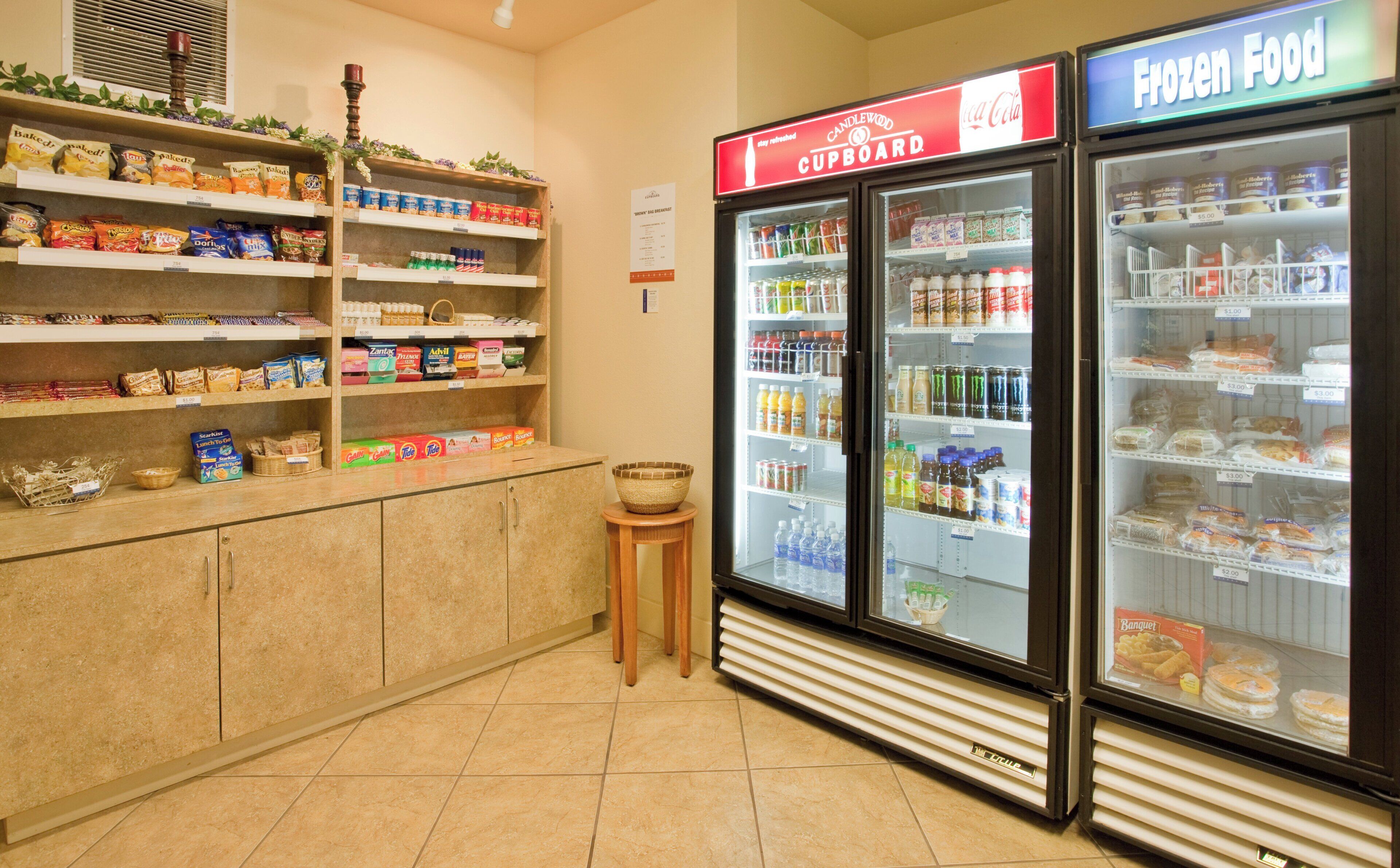A grocery store interior with shelves stocked with snacks, a refrigerated section, and a freezer.