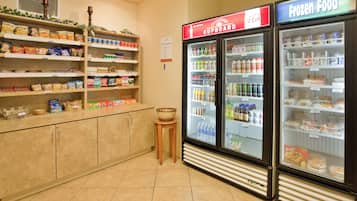 A grocery store interior with shelves stocked with snacks, a refrigerated section, and a freezer.