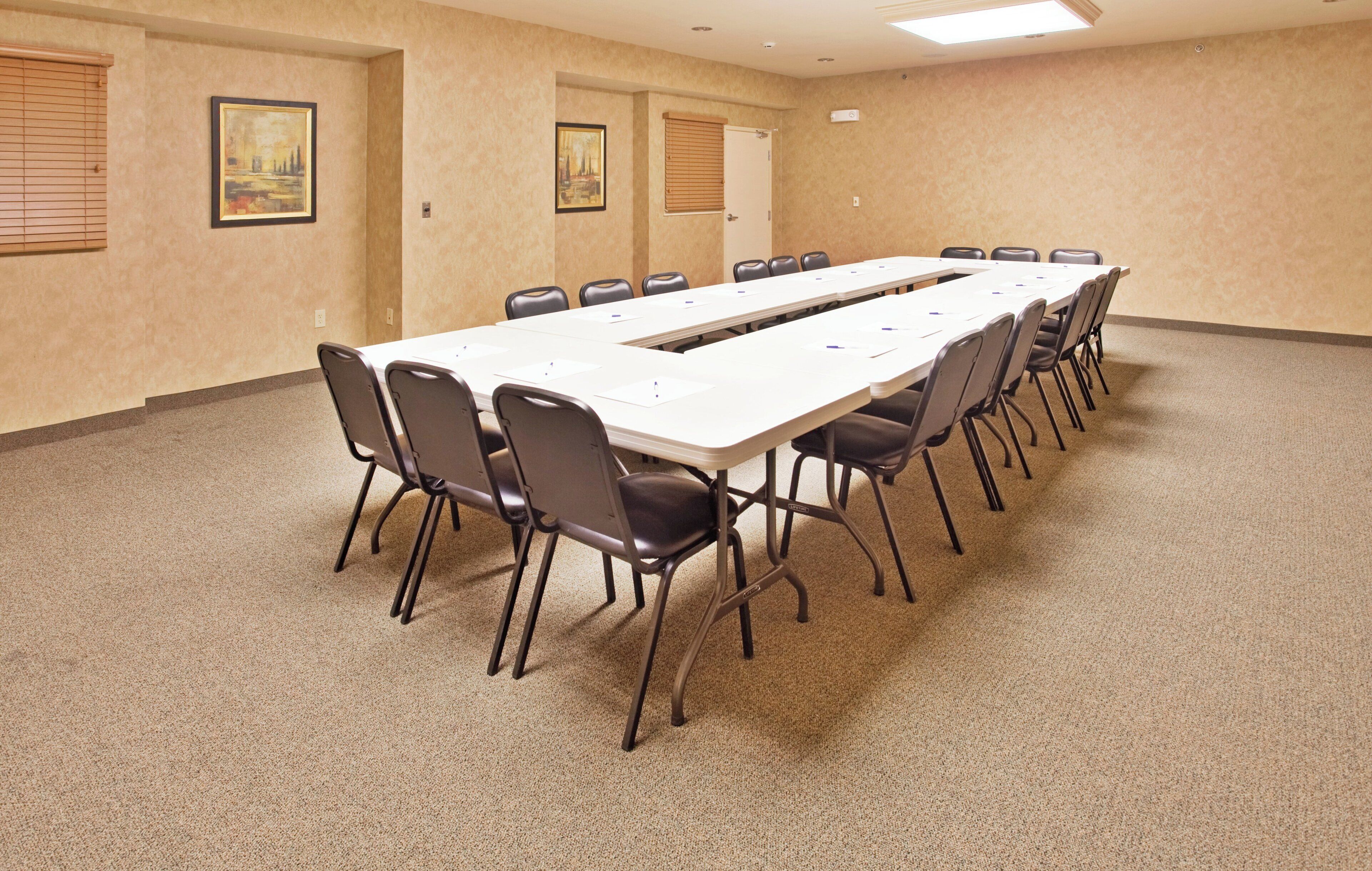 A conference room with a long table and chairs, carpeted floor, and two doors with windows.