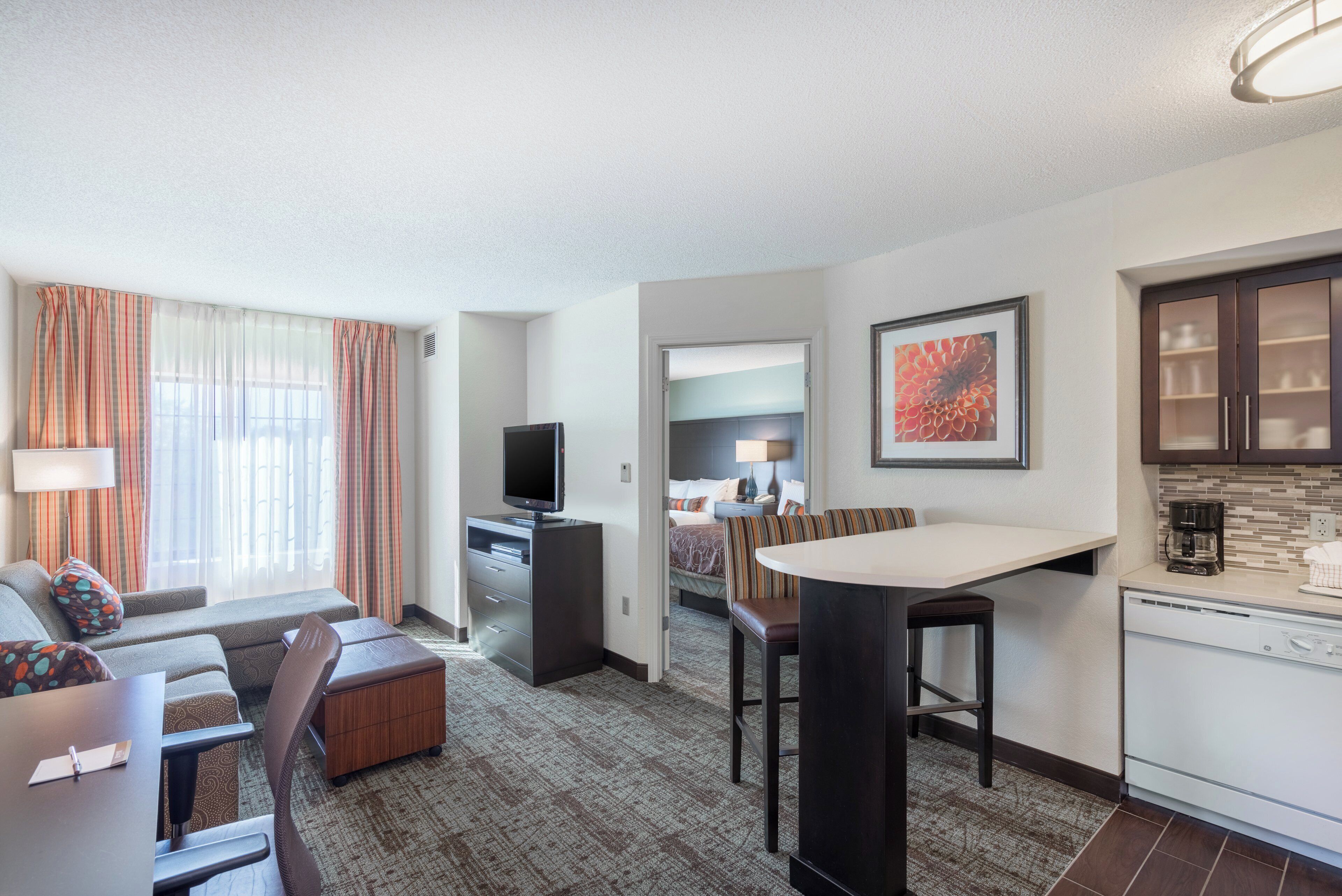 A hotel room with a living area, kitchenette, and a bed.