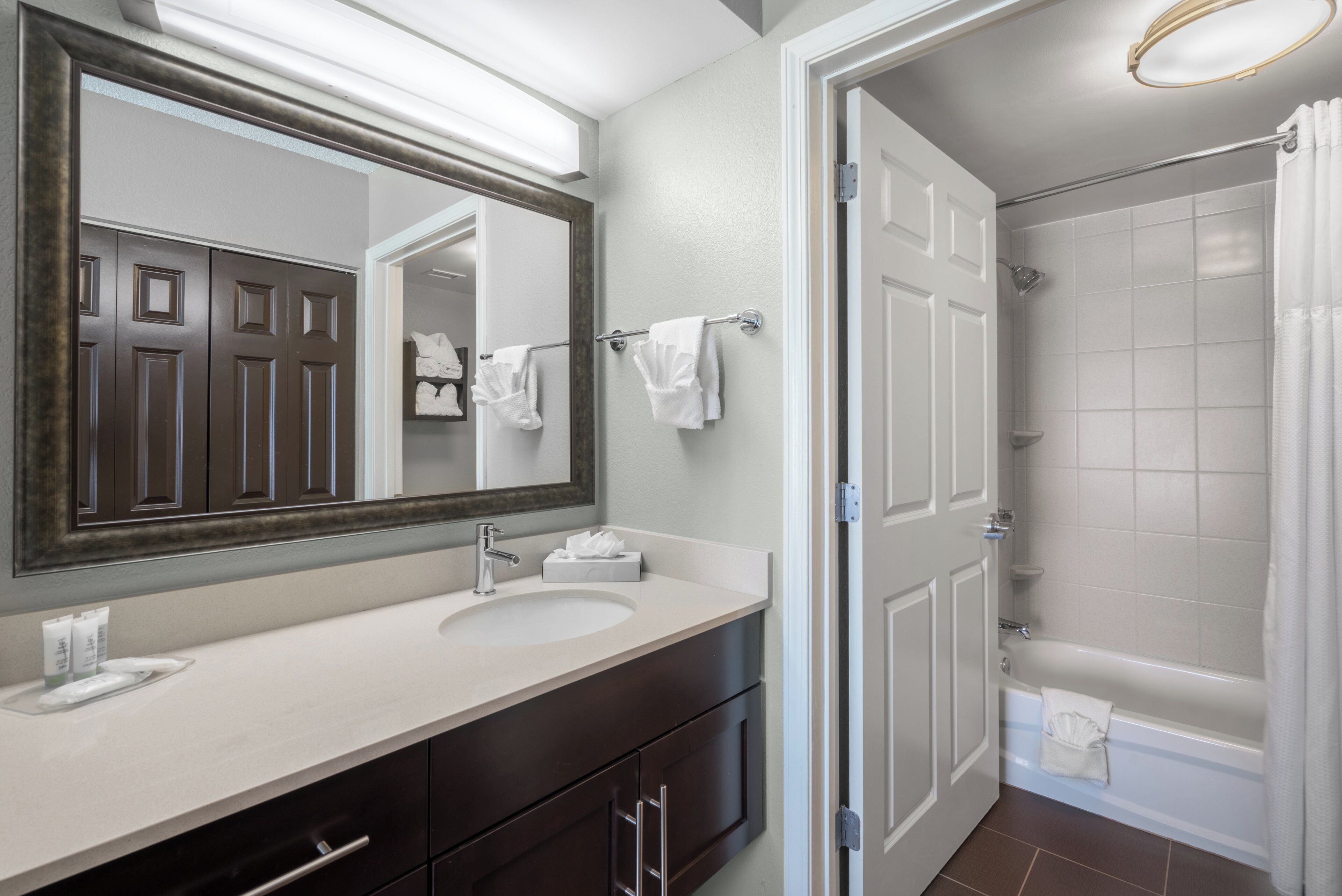 A bathroom with a large mirror, a sink, a toilet, and a shower.