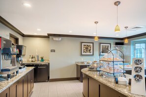 Een moderne keuken met een koffieapparaat, een spoelbak en een buffet met verschillende soorten eten.