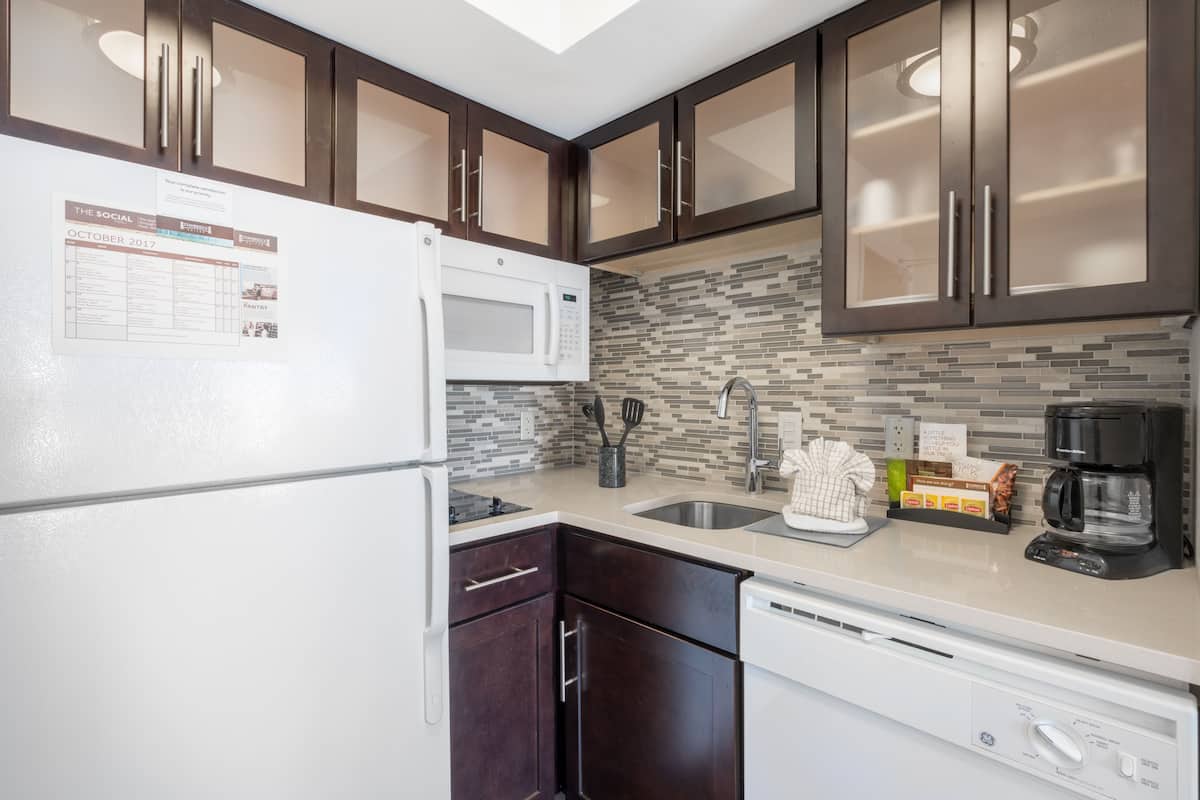 Une cuisine moderne avec des meubles de rangement en bois foncé, un réfrigérateur blanc, un four à micro-ondes, un évier et un lave-vaisselle.